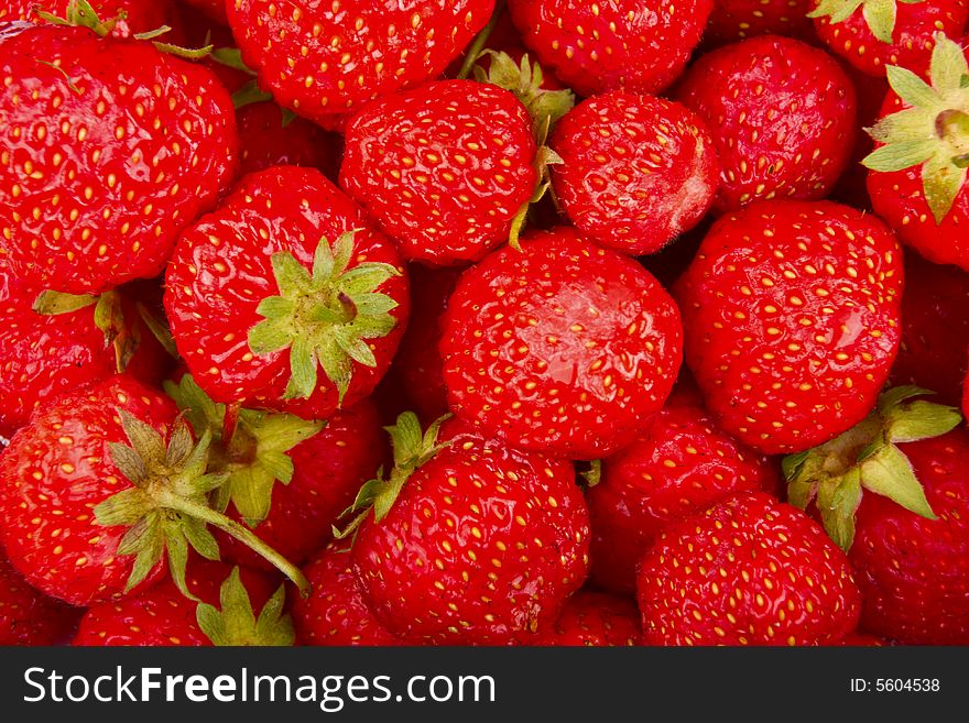 Red fresh strawberries with green leaves background