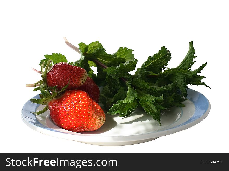 On a plate with the blue border shined with beams of the sun, the strawberry and mint leaves lies