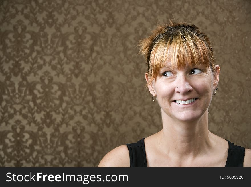 Pretty woman smiling in front of a gold-flocked wallpaper background