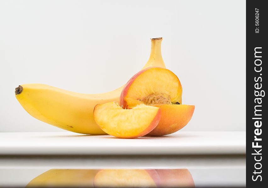 A sliced peach and ripe banana on white background. A sliced peach and ripe banana on white background.