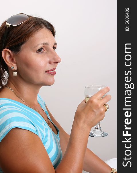 Adult Female Model wearing a blue top with a glass of wine. Adult Female Model wearing a blue top with a glass of wine