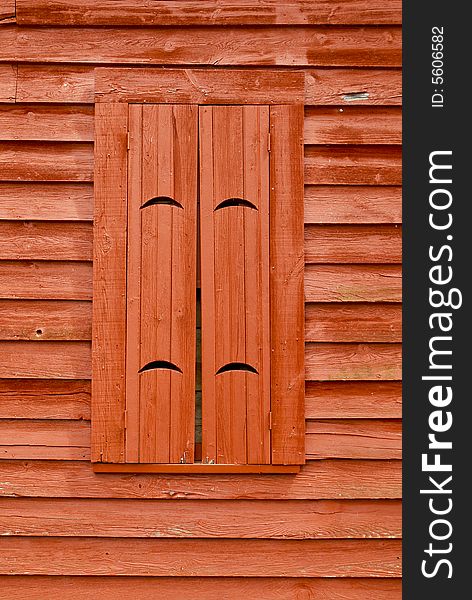 Red, weathered, wooden window shutters on same color wood siding wall. Red, weathered, wooden window shutters on same color wood siding wall.