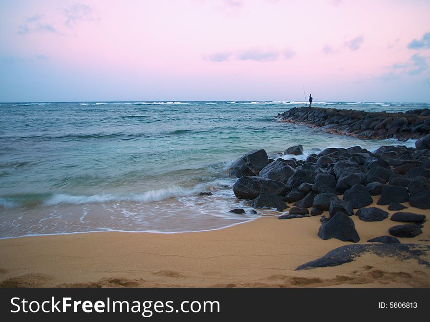 Beach sunset with fisherman on rock pier. Beach sunset with fisherman on rock pier