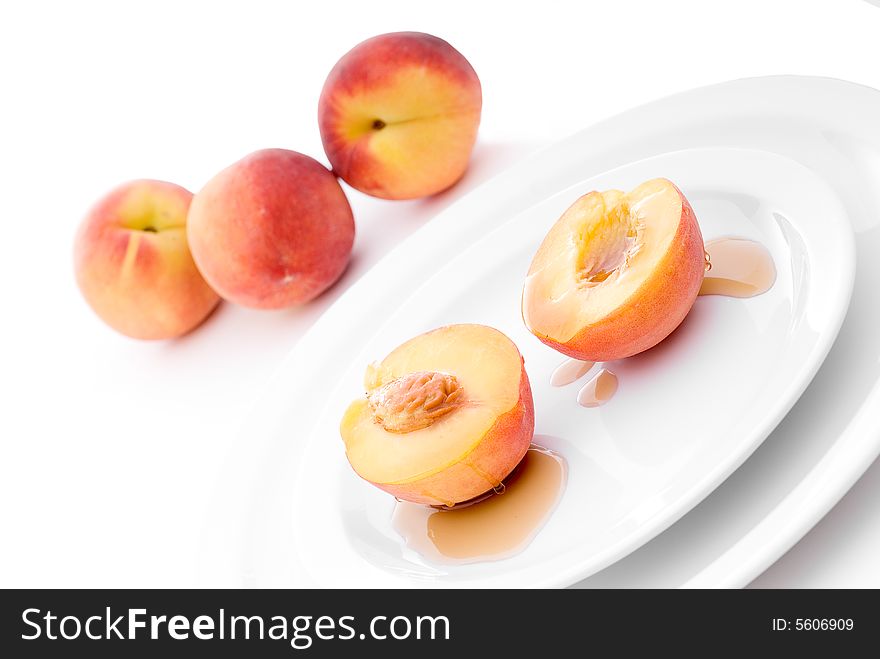 Shallow focus fresh peaches drizzled with maple syrup on a white plate. Shallow focus fresh peaches drizzled with maple syrup on a white plate