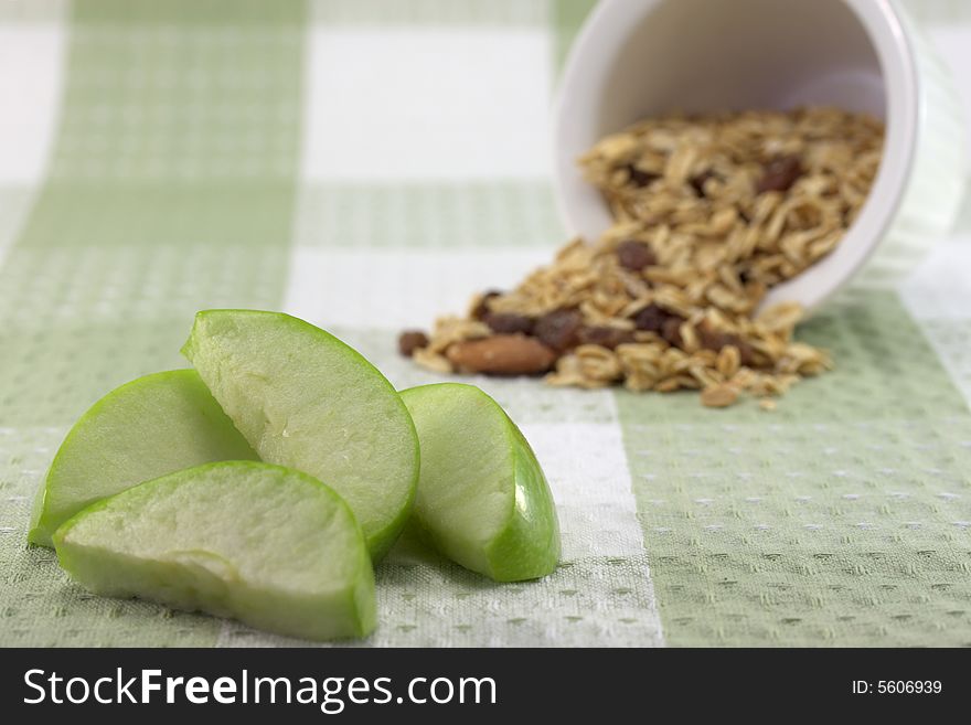 A sliced green apple with a bowl of muesli. A sliced green apple with a bowl of muesli.