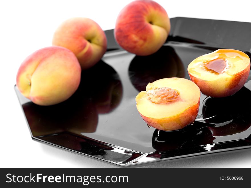 Shallow focus fresh peaches with syrup on a black plate