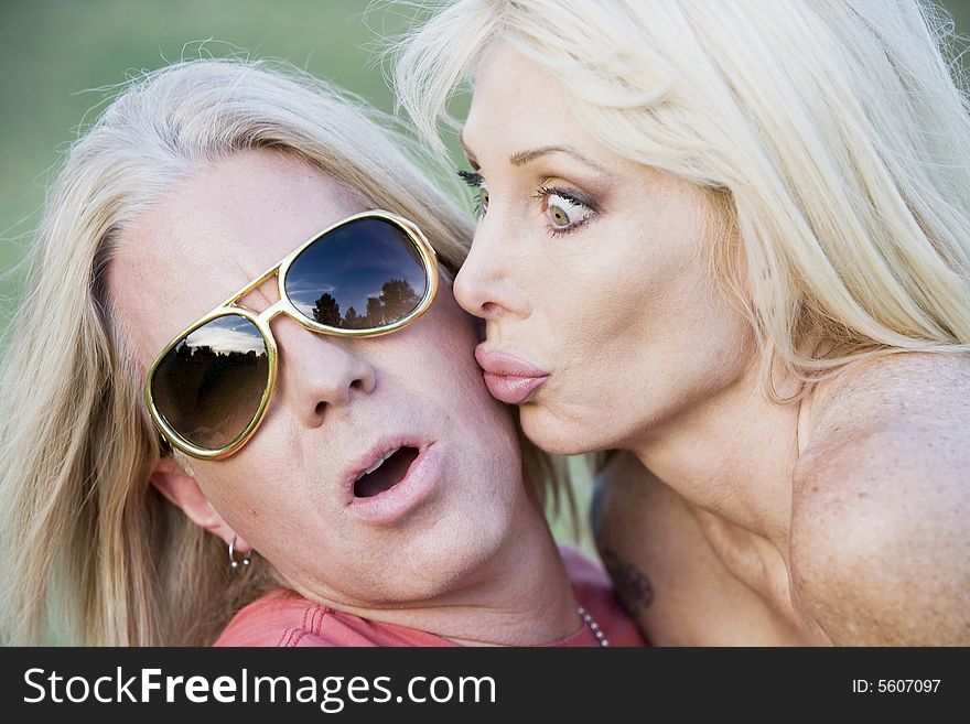 Woman with big eyes kissing a surprised and pleased man. Woman with big eyes kissing a surprised and pleased man