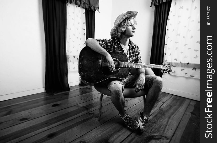 Young musician with an old guitar in an empty room. Young musician with an old guitar in an empty room