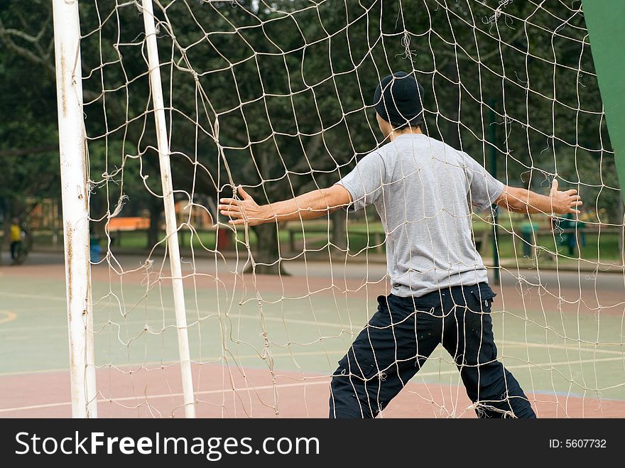 A man, standing with his arms wide open, in front of the goalie net, acting to be a soccer goalie. - horizontally framed. A man, standing with his arms wide open, in front of the goalie net, acting to be a soccer goalie. - horizontally framed