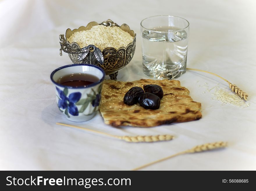 Iftar glass of water and black dates and cup on tea plus wheat and rice. Iftar glass of water and black dates and cup on tea plus wheat and rice