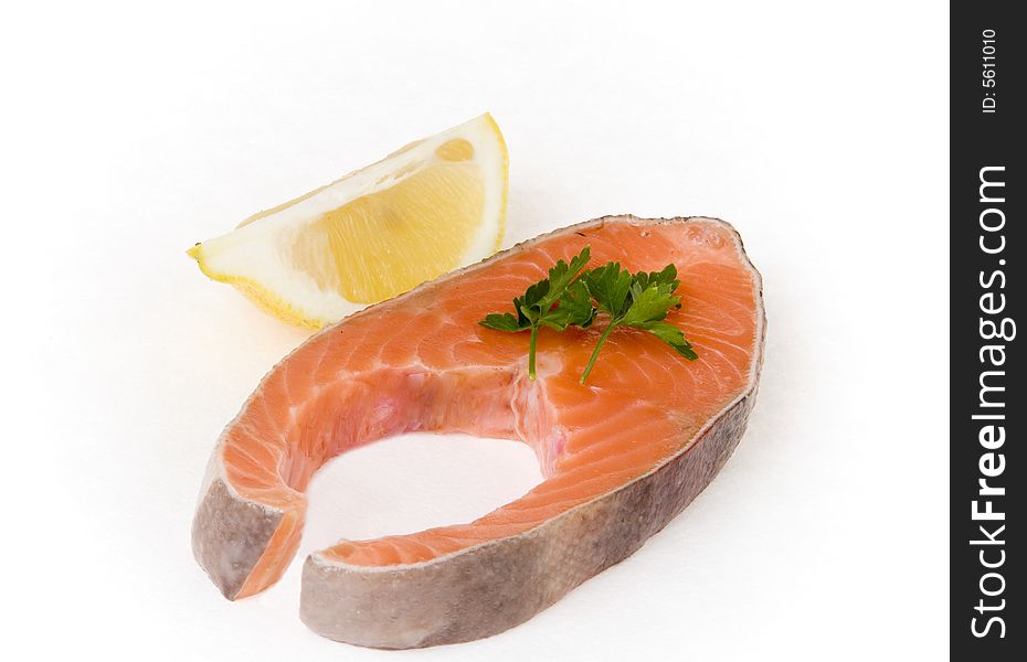 Salmon steak with lemon segment on white ground
