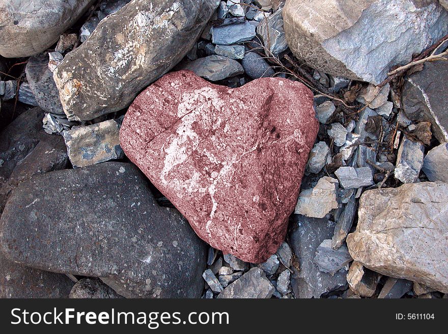 Pink stone in the shape of a heart among rocks. Pink stone in the shape of a heart among rocks