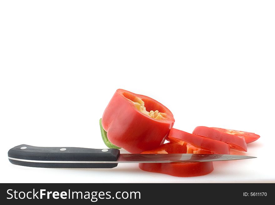 A red bell pepper, cut in slices, and a knife. A red bell pepper, cut in slices, and a knife