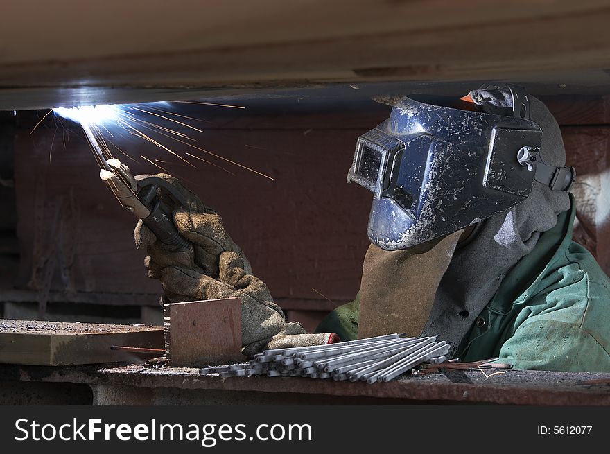 A welder working at shipyard during night shift. A welder working at shipyard during night shift