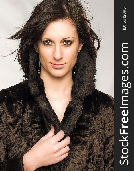 Attractive young female with flowing dark brown hair wearing a brown mock-fur coat. Attractive young female with flowing dark brown hair wearing a brown mock-fur coat.