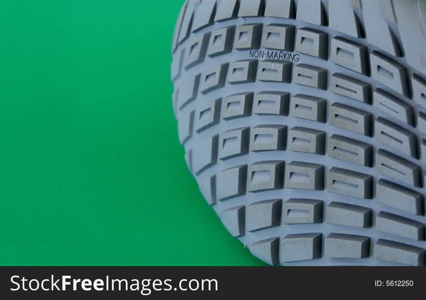 Macro pattern of rubber sole of sneakers against green