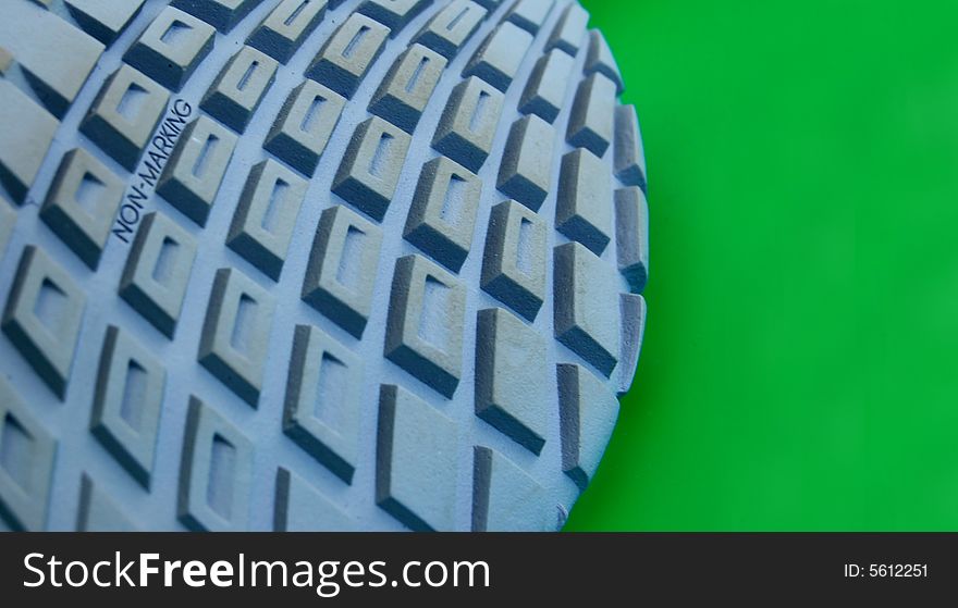 Macro pattern of rubber sole of sneakers against green