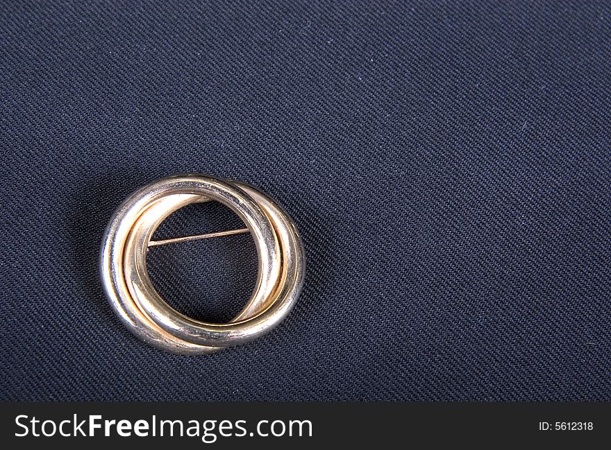 A gold pin of interlocking circles. A gold pin of interlocking circles