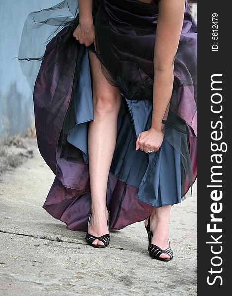 A woman tears her bridesmaid dress on a city street. A woman tears her bridesmaid dress on a city street