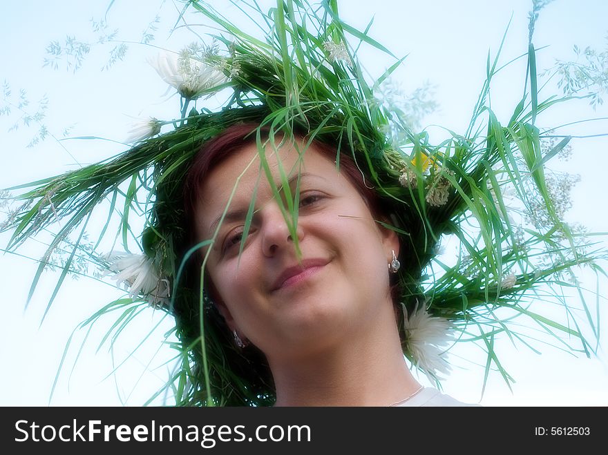 The young woman with a wreath from grasses and colours on a head. The young woman with a wreath from grasses and colours on a head