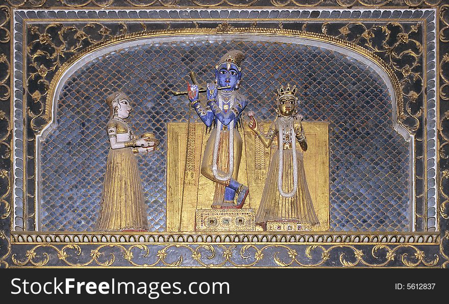 Colored statues encrusted with gems of hindu god Vishnu playing flute with goddesses on blue ceramics background in the maharajah palace of bikaner, Rajasthan, India. Colored statues encrusted with gems of hindu god Vishnu playing flute with goddesses on blue ceramics background in the maharajah palace of bikaner, Rajasthan, India.