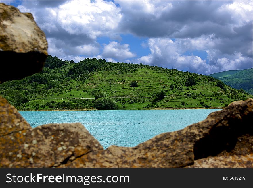 A view of mountain landscape with a small lake and some rocks. A view of mountain landscape with a small lake and some rocks