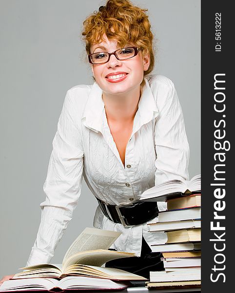 Young pretty woman with eyeglasses over table with books. Young pretty woman with eyeglasses over table with books