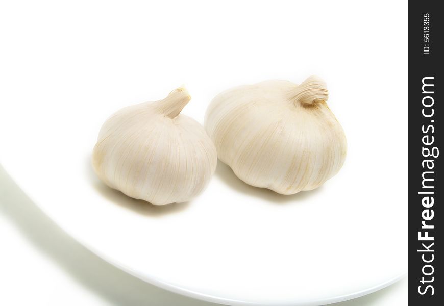 Two bulbs of garlic on white plate and isolated on white background. Two bulbs of garlic on white plate and isolated on white background