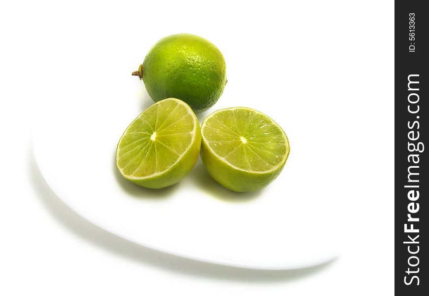 A group of half and whole fresh limes on white plate and isolated on white background. A group of half and whole fresh limes on white plate and isolated on white background