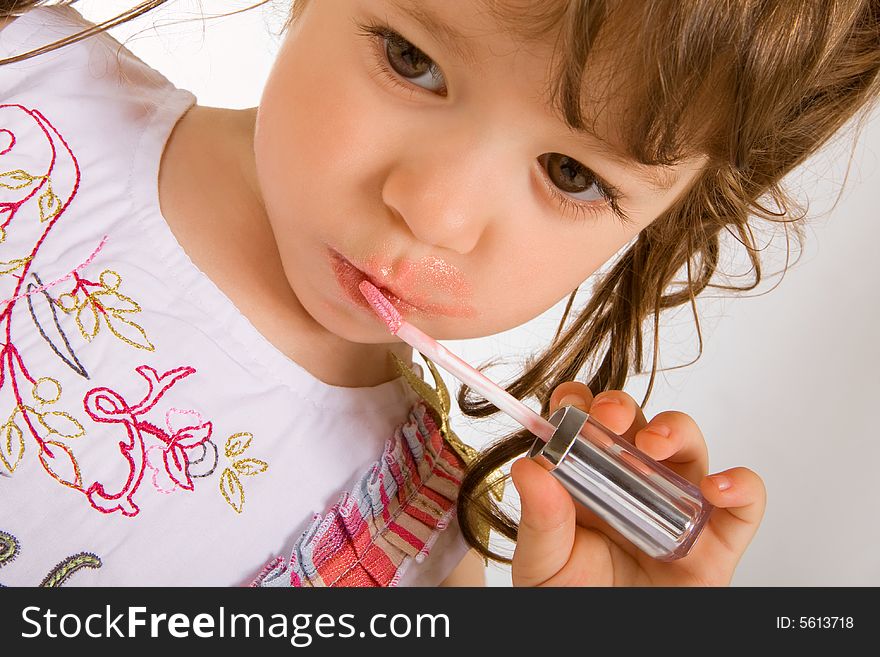 Adorable little girl applying make-up with lipstick