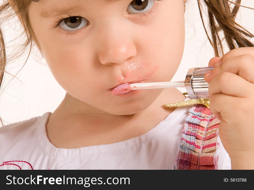 Adorable little girl applying make-up with lipstick