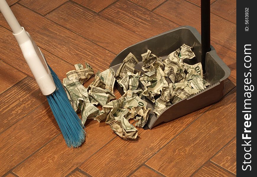 Photo of  a broom and dust pan sweeping up money. Photo of  a broom and dust pan sweeping up money