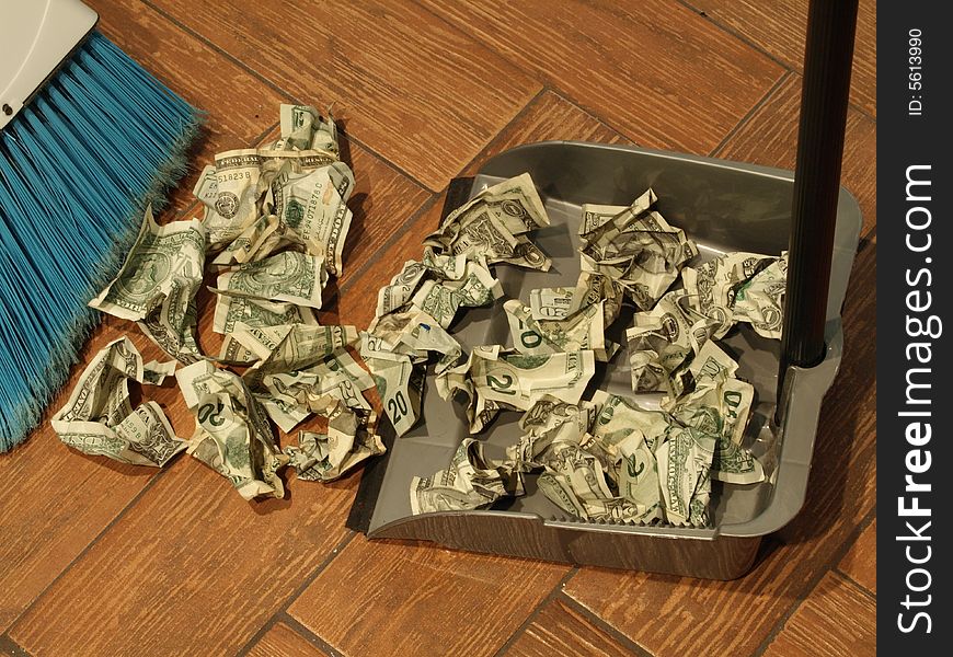 Photo of a broom and dust pan sweeping up money. Photo of a broom and dust pan sweeping up money