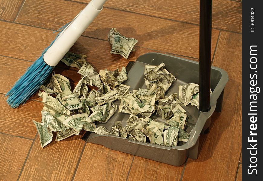 Photo of a broom and dust pan sweeping up money. Photo of a broom and dust pan sweeping up money