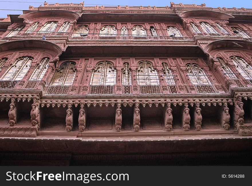 Wide windows, sculpted pillars arches and balconies on this red sand stone front of a palace in Bikaner, Rajasthan, India. Wide windows, sculpted pillars arches and balconies on this red sand stone front of a palace in Bikaner, Rajasthan, India.