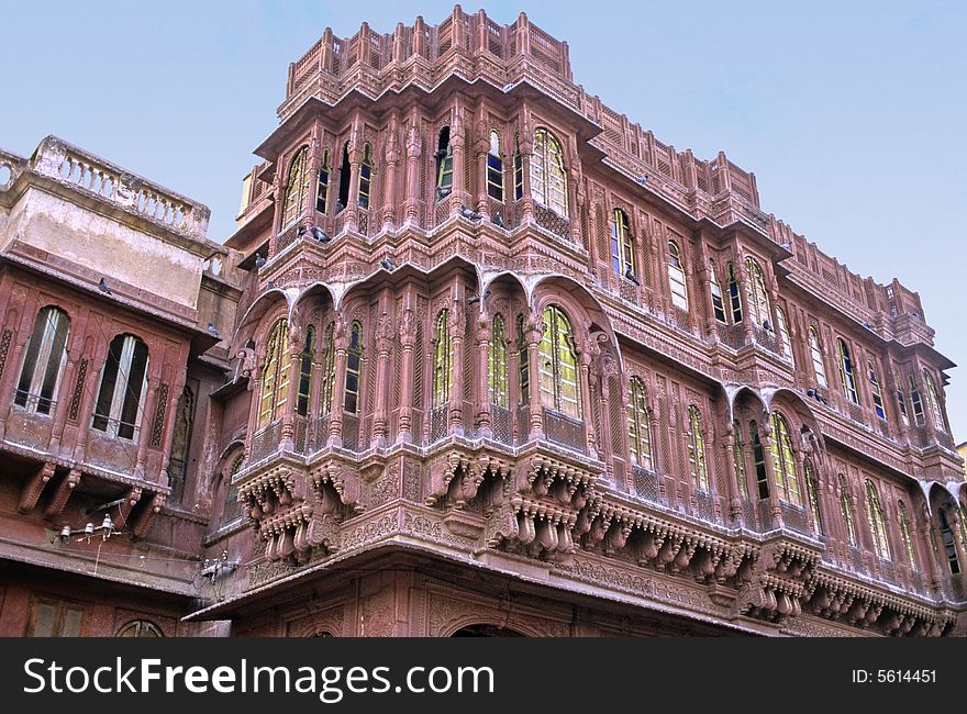 Wide windows, sculpted pillars arches and balconies on this red sand stone front of a palace in Bikaner, Rajasthan, India. Wide windows, sculpted pillars arches and balconies on this red sand stone front of a palace in Bikaner, Rajasthan, India.