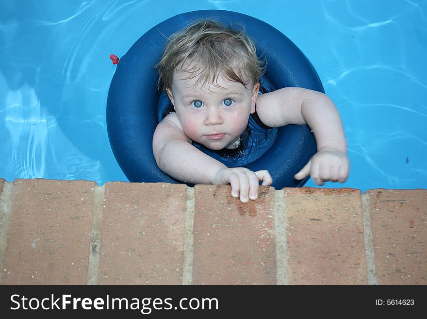 A baby girl wearing her bentley belt swimming in the pool on a hot summer's day. A baby girl wearing her bentley belt swimming in the pool on a hot summer's day.