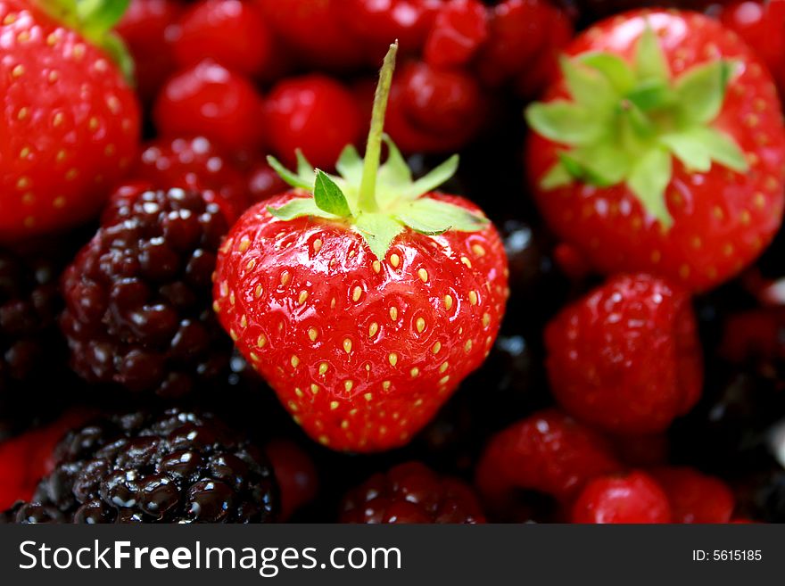 Close-up of a ripe strawberry on a background of mixed fruit. Close-up of a ripe strawberry on a background of mixed fruit