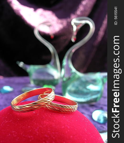 Wedding rings on the red box with glass swans