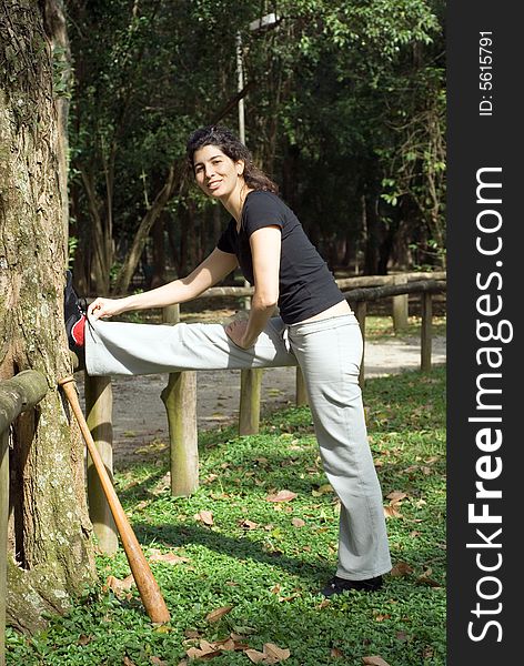 Woman Stretching Her Leg By a Tree - Vertica