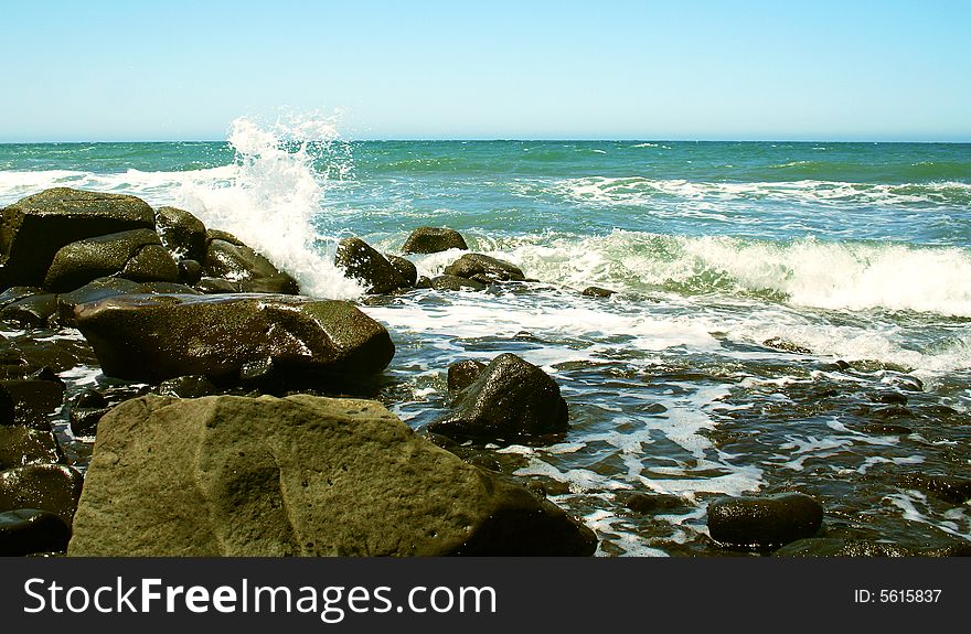 Waves Break on the Rocky Shore of a Blue-Green Sea. Waves Break on the Rocky Shore of a Blue-Green Sea