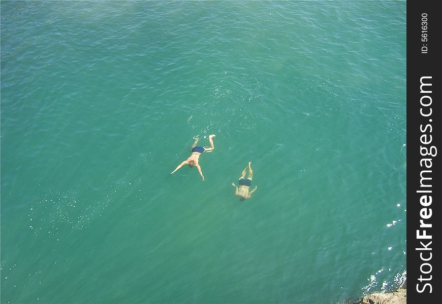 Jump from a high rock in water and swim in the sea