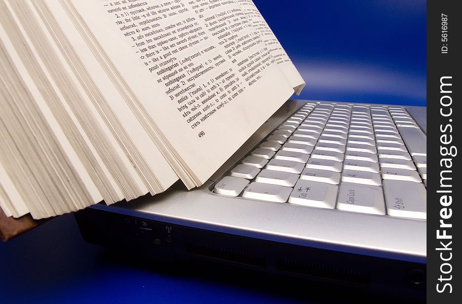 Book on laptop on blue background