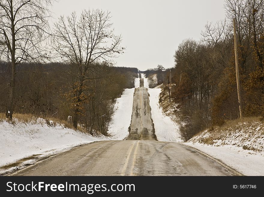 Rural midwestern winter road bordered by woods. Rural midwestern winter road bordered by woods