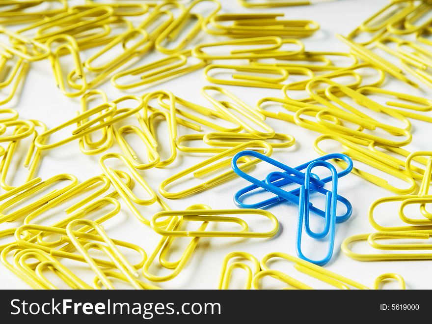 A pile of paperclips on white background with 3 standing out in the crowd