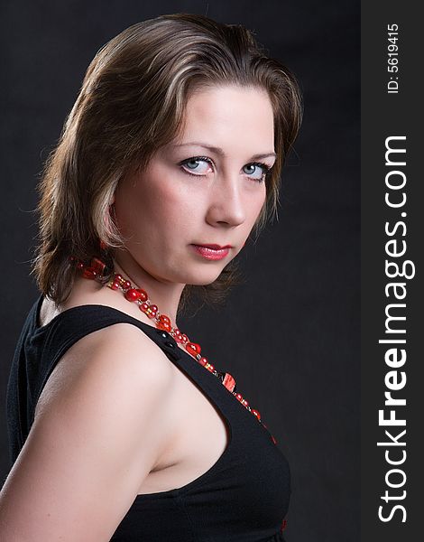 Portrait of the beautiful young girl in a red beads on a dark background. Portrait of the beautiful young girl in a red beads on a dark background