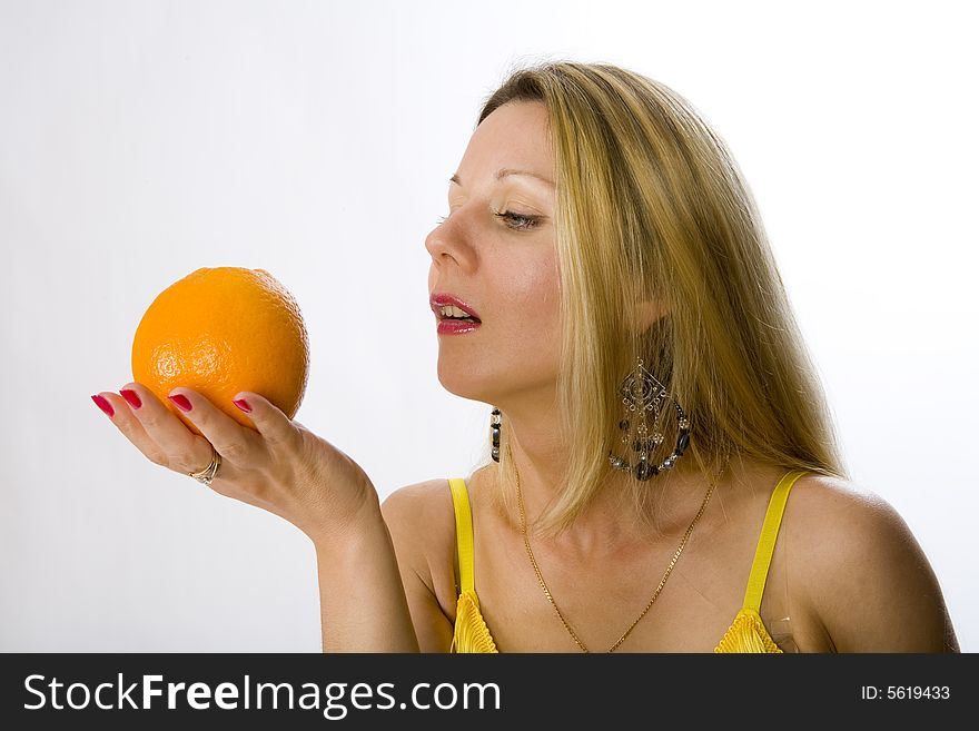 Blonde woman in yellow dress with orange in her hand. Blonde woman in yellow dress with orange in her hand