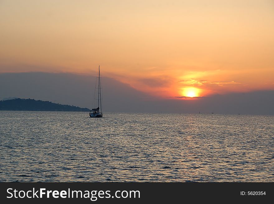 On an early morning, a sailboat sails into the sunrise. On an early morning, a sailboat sails into the sunrise