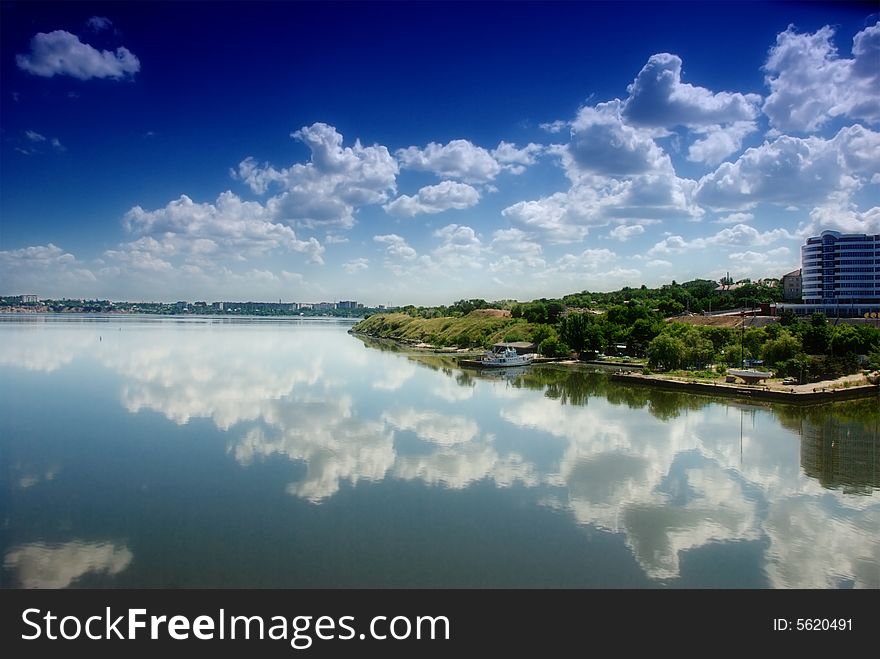 Cloudy blue sky reflection in calm water. Cloudy blue sky reflection in calm water