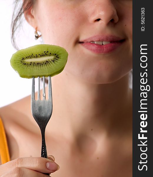 Beautiful caucasian teen eats kiwi with fork. Beautiful caucasian teen eats kiwi with fork